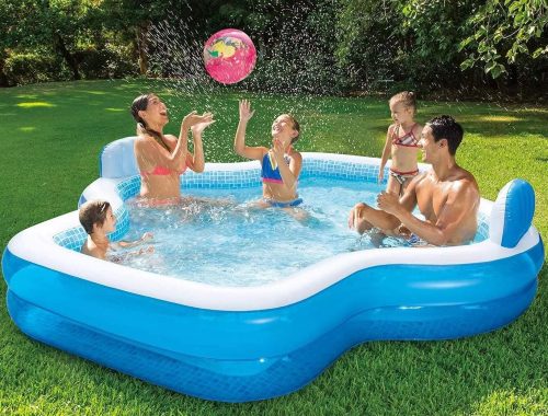 A family enjoys a sunny day playing with a beach ball in an inflatable pool with two built-in seats and backrests.