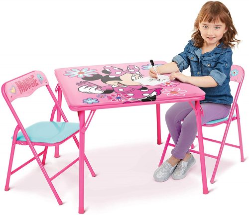 A little girl sitting and drawing on kid's table